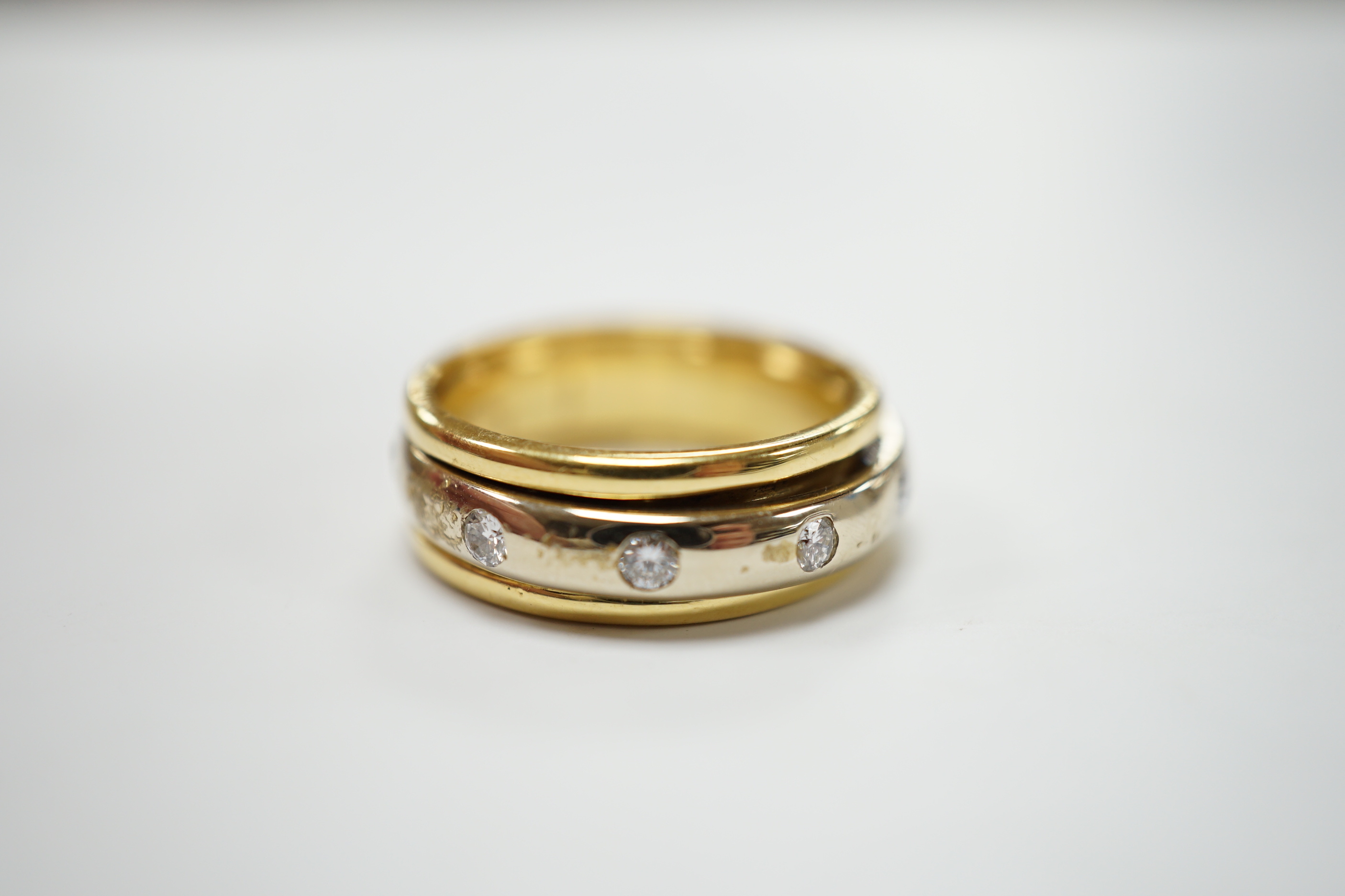 A modern 750 yellow metal ring, with central diamond set rotating white metal band (stone missing), size P/Q, gross weight 7.9 grams.